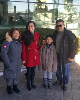 Rebecca wears a red coat and poses outside a restaurant at Niagara Falls her father, aunt, and little brother. Rebecca is half-Filipino and half white.