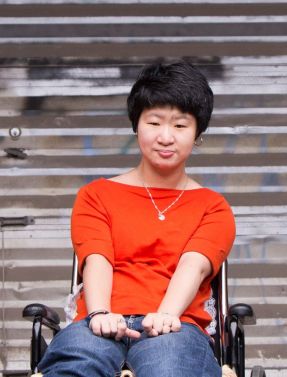 Author photo of Erin shows her wearing a a stylish red shirt and seated in her wheelchair